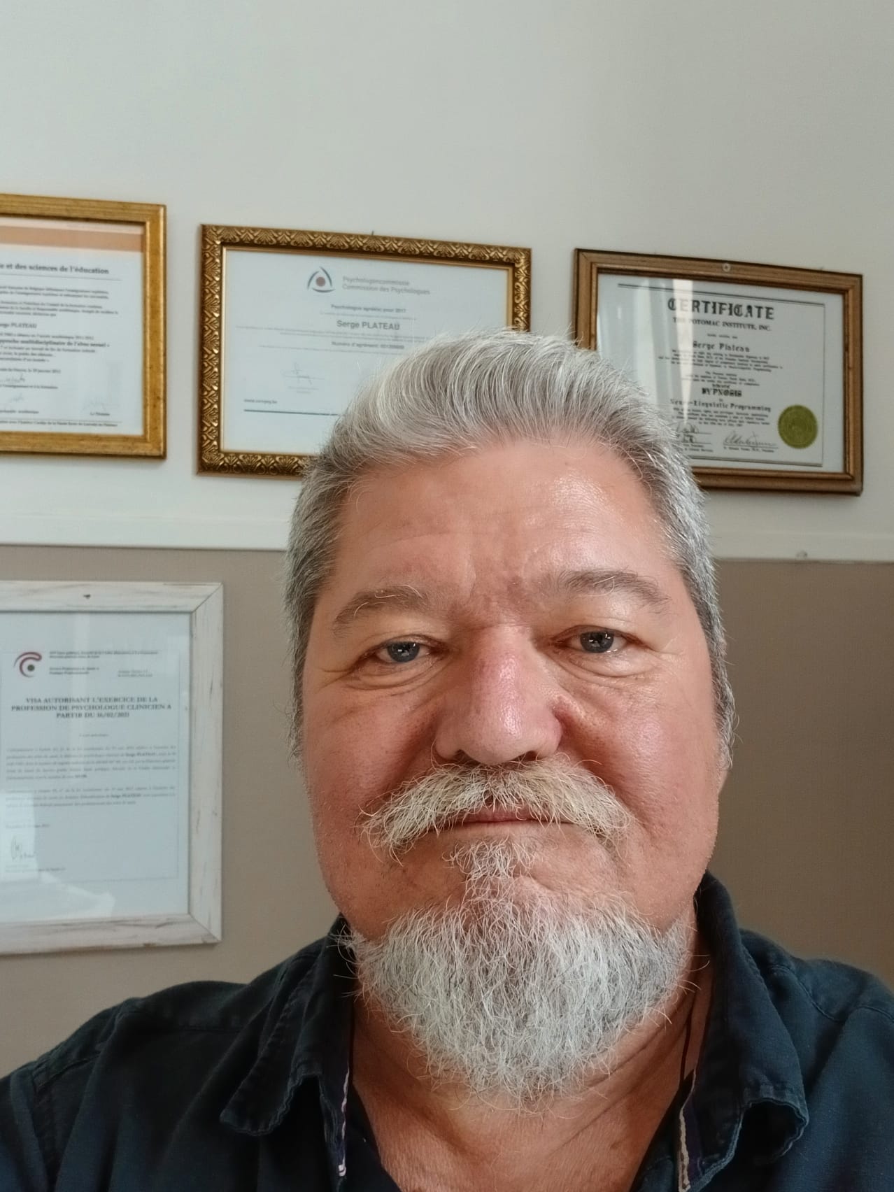 Serge Plateau devant ses diplômes et agréments